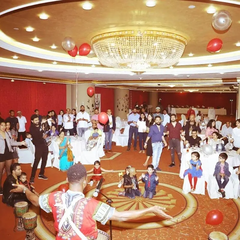 African drummer getting children and families involved at a celebration in a Dubai hotel ballroom