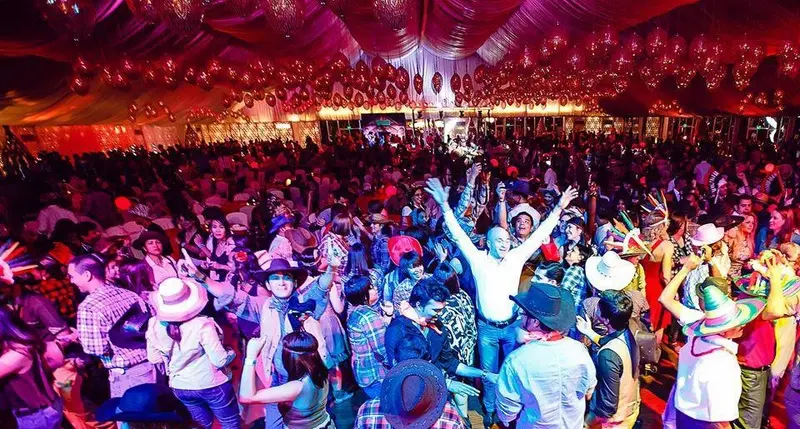Guests in cowboy hats dancing at a themed party in a decorated event tent in Dubai