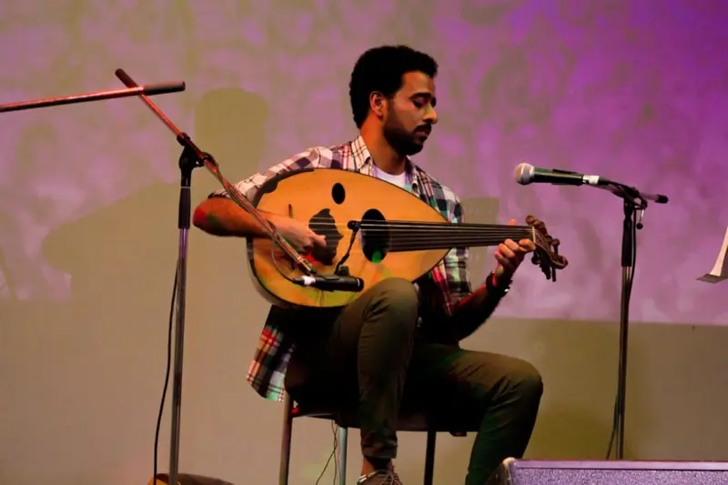 Oud player performing on stage at an event in Dubai