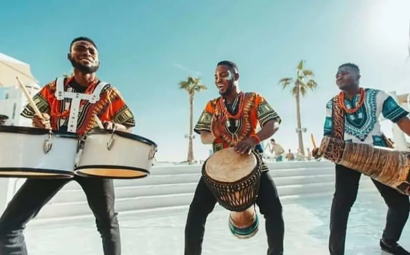 Three African drummers playing at an outdoor beach club event in Dubai